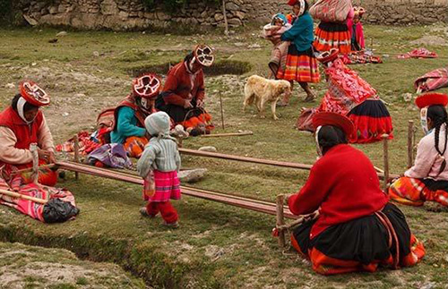 Peruvian women in the process of weaving with a help of a four-post loom