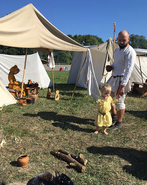 Medieval camp with adults and kids doing their chores