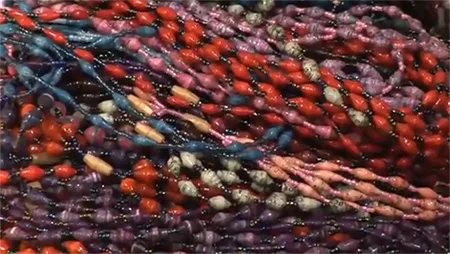 Ugandan women make beaded necklaces from recycled paper