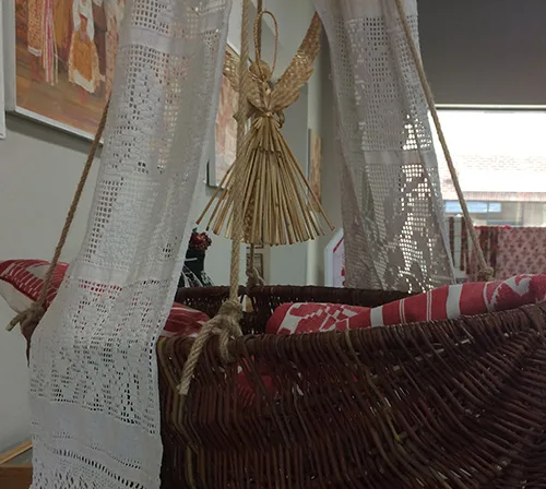 Willow crib with embroidered towels and straw doll amulet